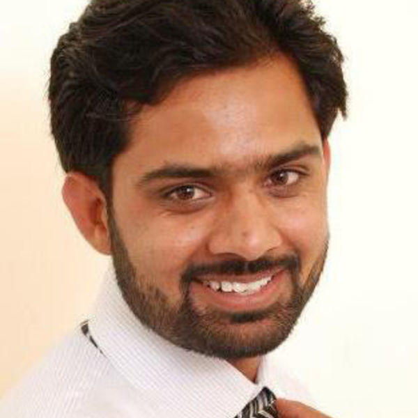 Close-up photo of Codeable expert Sajid Javed, wearing a shirt and tie and grinning