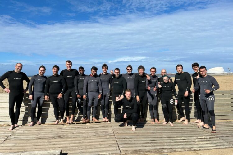 A group of 17 experts and staff in wet suits in front of a beach in Porto, Portugal.