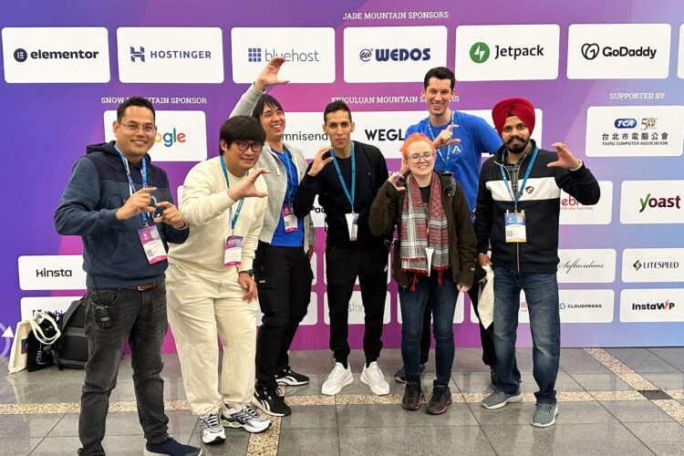 Surendra, Samuel, Dika, Ali, Megan, Xaver, and Simrandeep posing with their hands in the shape of a C for Codeable at WordCamp Asia in front of the sponsors backdrop.