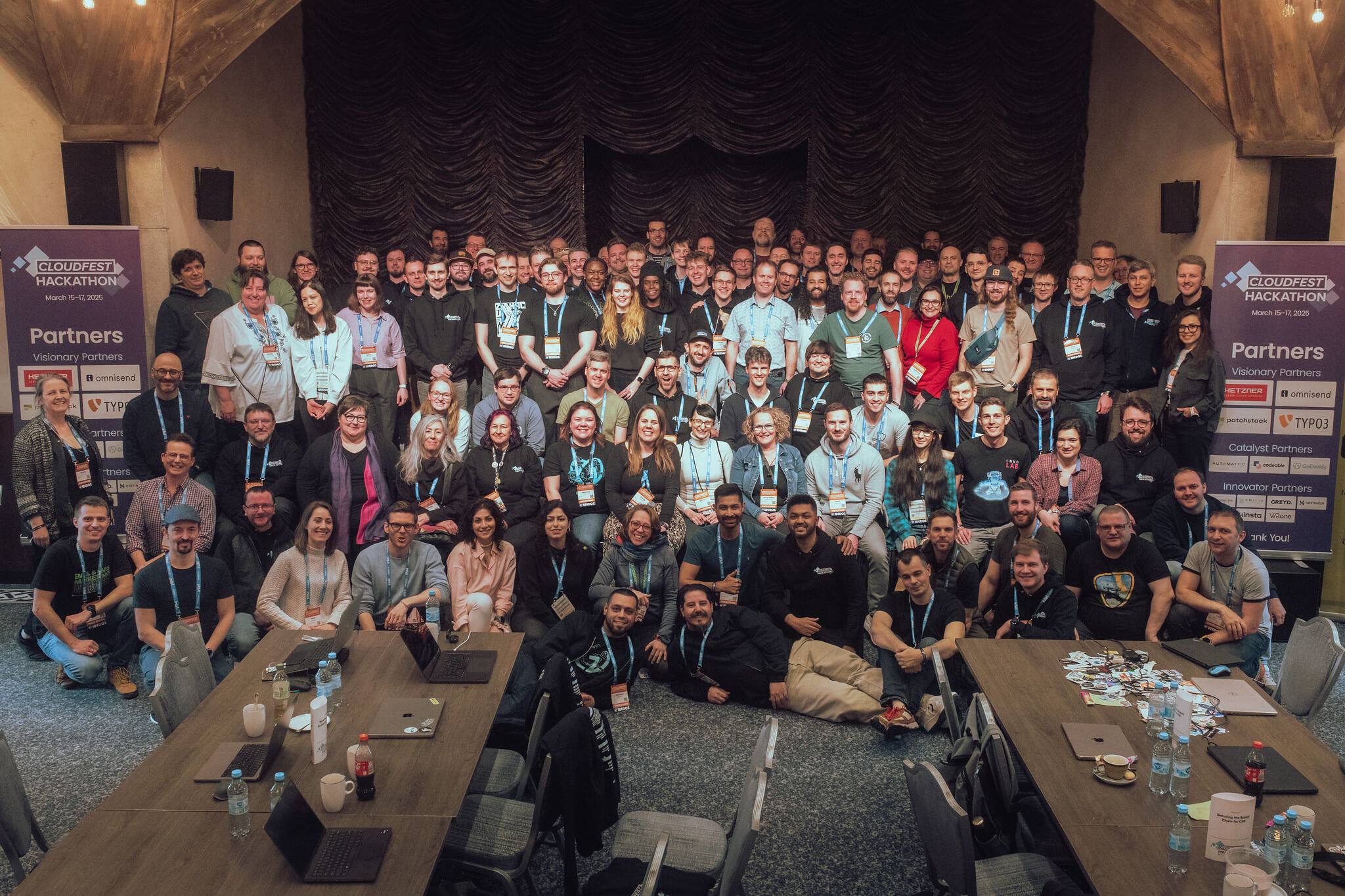 A group of more than 100 people in a room with smiles on their faces.